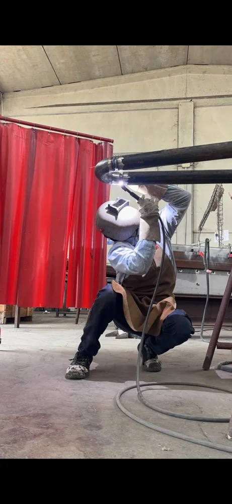 Saldatore al lavoro sul raccordo di una tubazione a U in officina