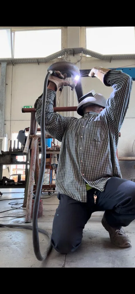 Operatore con maschera durante la saldatura di un raccordo tubiero in officina